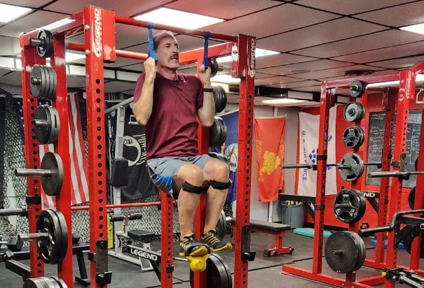 man in red shirt hanging on gym equipment
